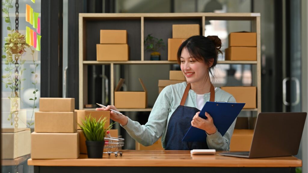 femme cheffe d'entreprise derrière comptoir compte cartons avec bloc-note